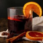 Apple cider sangria in a clear class with an orange slice on the rim