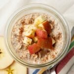 Apple cinnamon overnight oats in a glass jar sitting on a striped kitchen towel