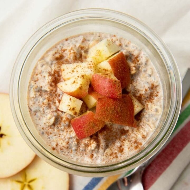 Apple cinnamon overnight oats in a glass jar sitting on a striped kitchen towel
