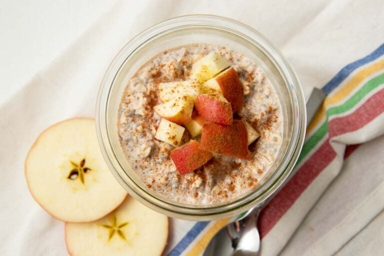 Top view of a glass jar of apple cinnamon overnight oats garnished with chopped apples and cinnamon.