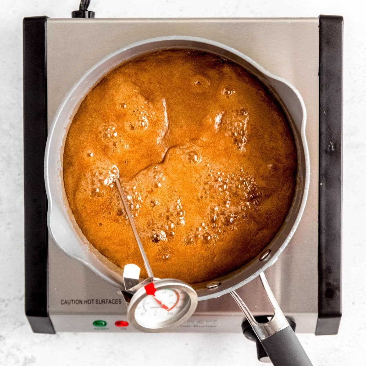 Caramel boiling in saucepan with a candy thermometer