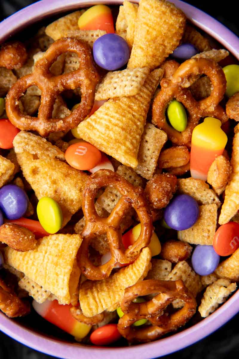 Close view of sweet and salty snack mix in a purple bowl.