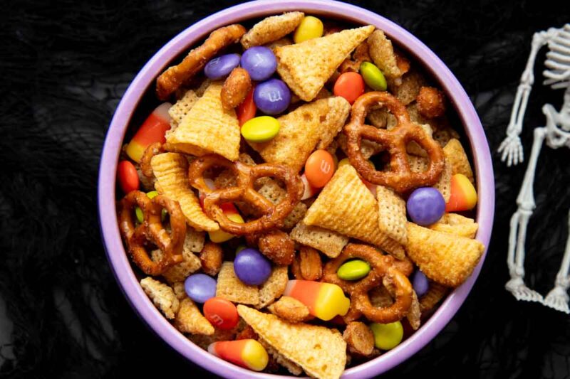 Top view of a bowl of Halloween chex mix on a black background.