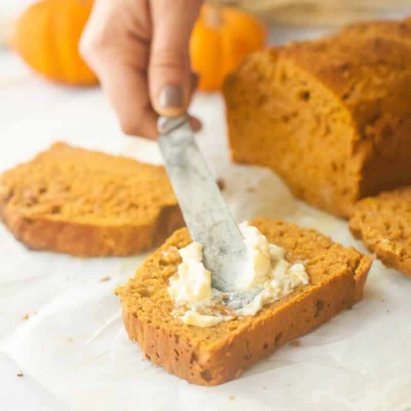 Spreading butter on a slice of healthy pumpkin bread