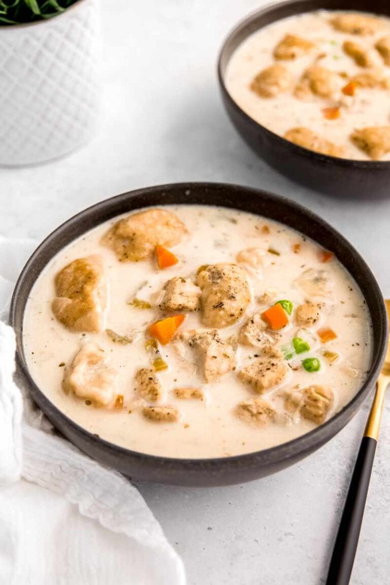 A dark serving bowl filled with creamy instant pot chicken and dumplings soup on a light background.