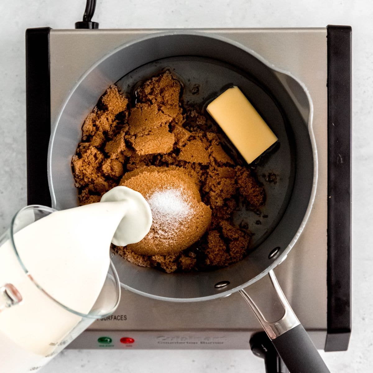 Pouring heavy cream into a saucepan while making caramel