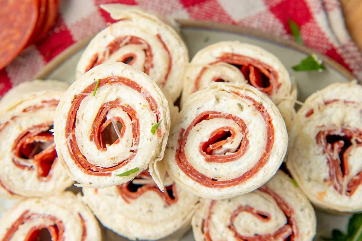 Top view of two pepperoni pinwheels atop other pinwheel bites, the pepperoni spirals deliciously displayed.