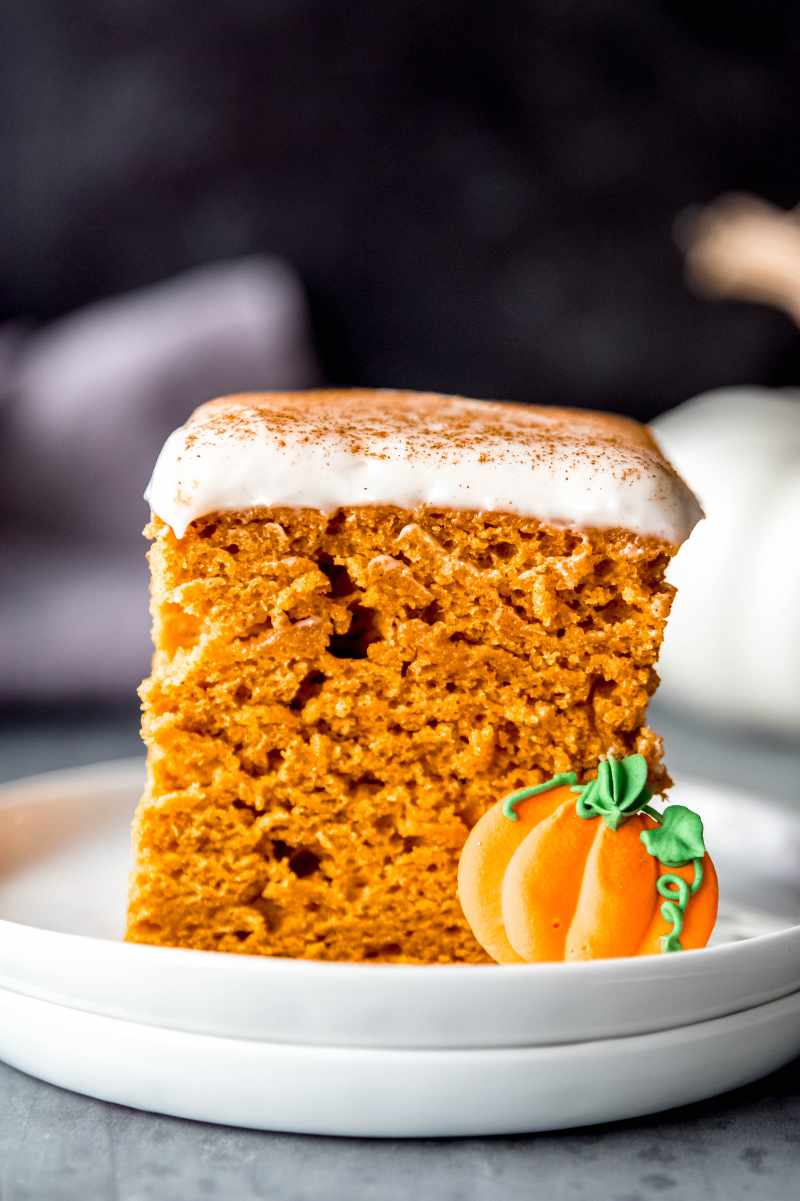 Close view of a tall slice of pumpkin cake with cream cheese frosting.