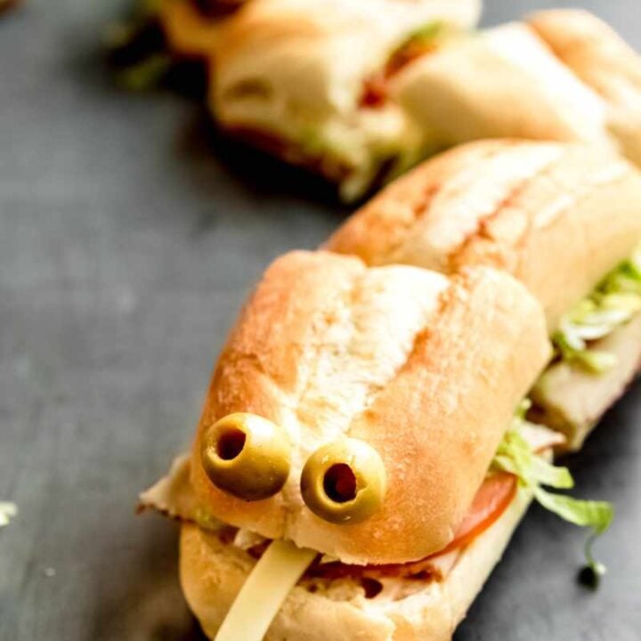 Halloween hoagies cut in half, arranged like a snake, and garnished with olive eyes and a forked tongue made of cheese.