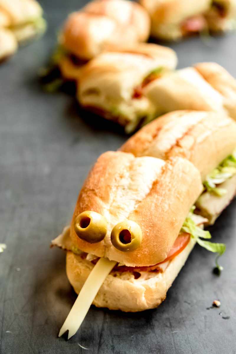 Halloween hoagies cut in half, arranged like a snake, and garnished with olive eyes and a forked tongue made of cheese.