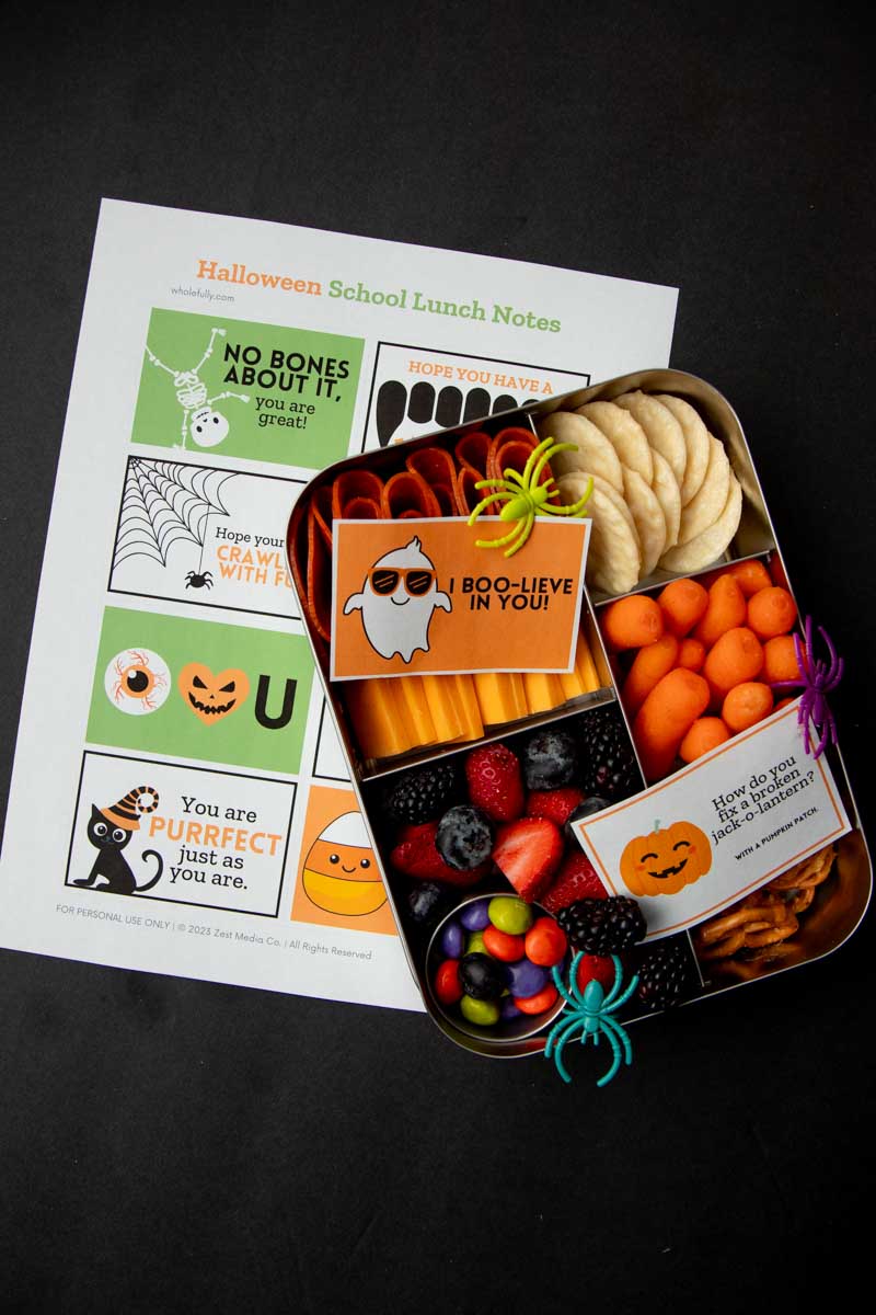 Spooky lunch notes under a lunchbox with two additional notes nestled in with the snacks.