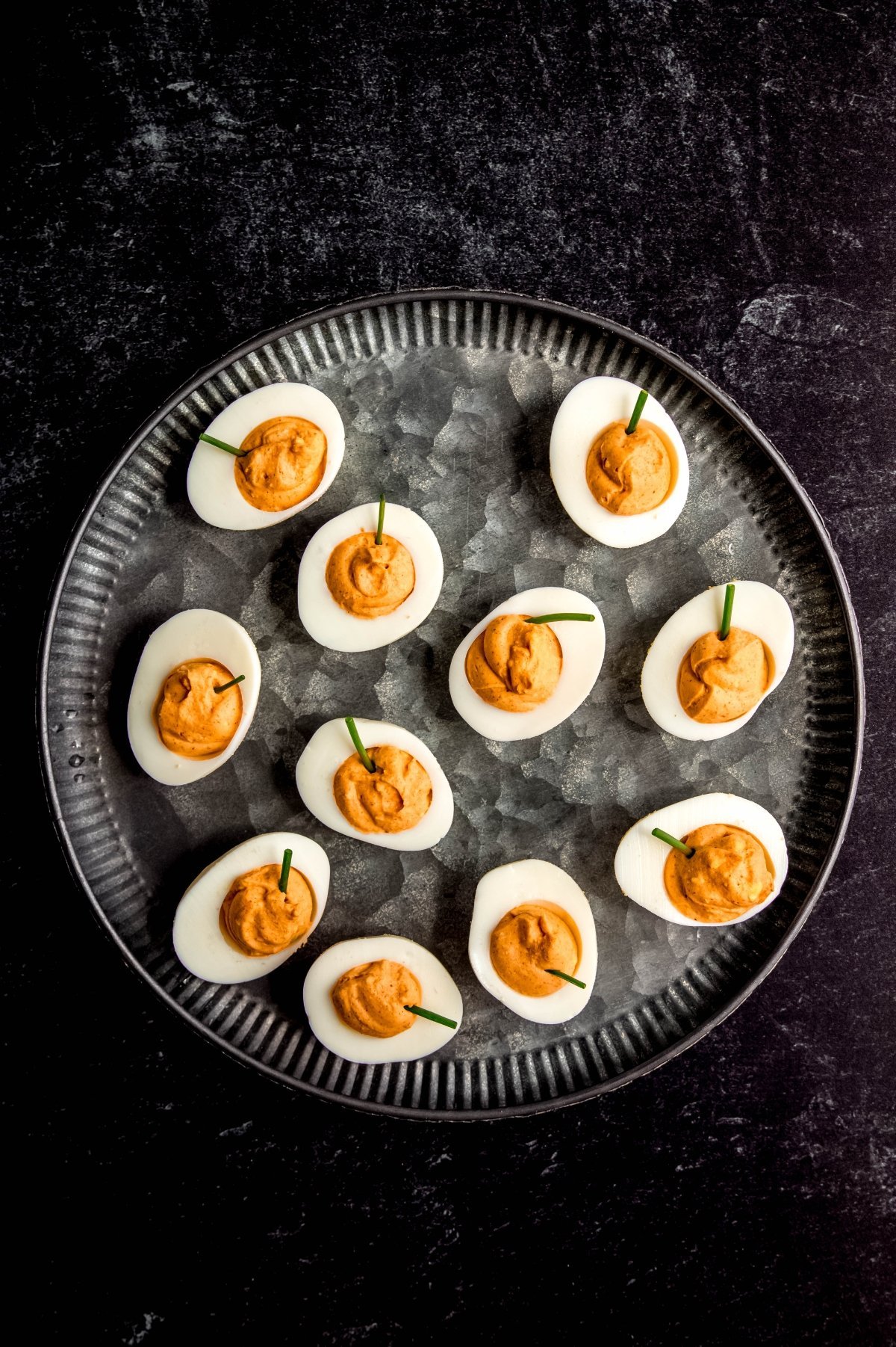 Halloween deviled eggs on a dark platter.