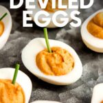 Close view of Halloween egg appetizers on a dark tray. A text overlay reads, "Halloween Deviled Eggs."