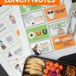 Sheets of notes and jokes for Halloween above a packed lunch with fruit, veg, and snacks. A text overlay reads, "Free Printable Halloween Lunch Notes."