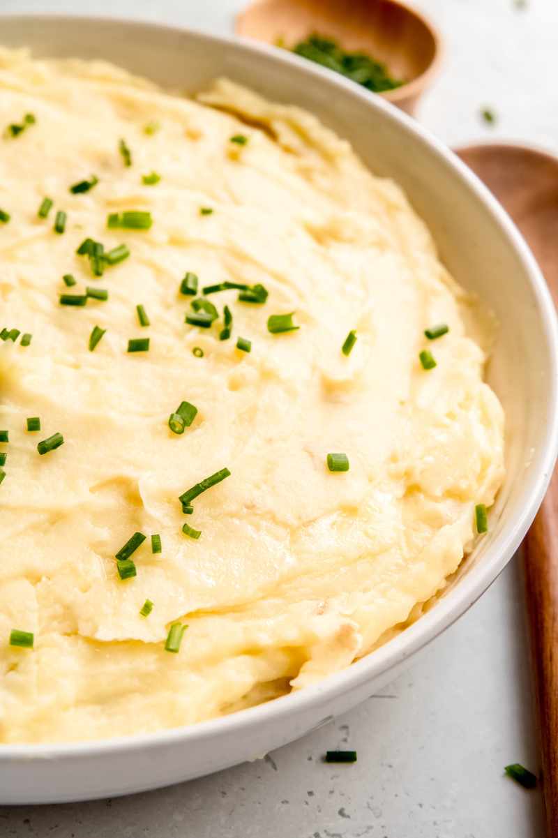 Pressure cooker mashed potatoes served in white bowl garnished with snipped chives.