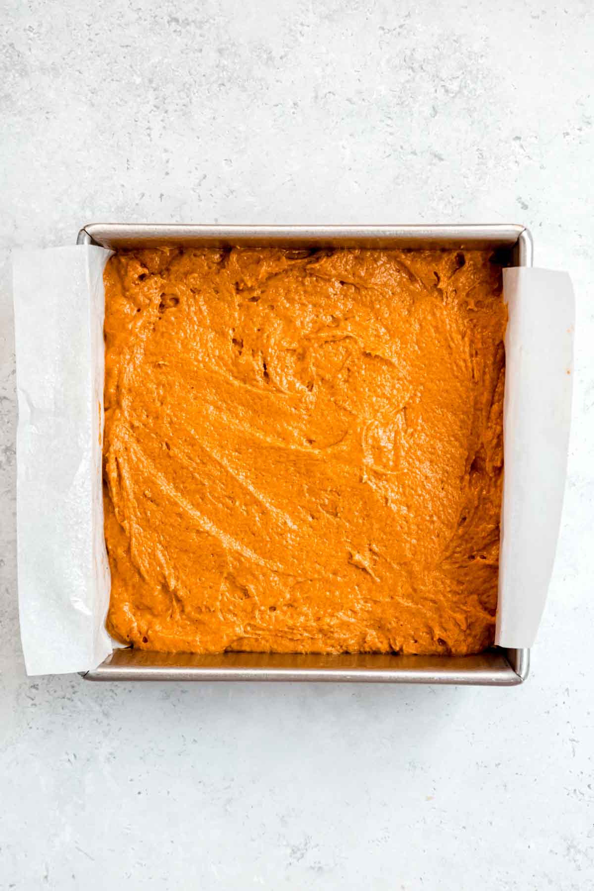 Unbaked pumpkin cake batter in a 8 x 8 square cake pan