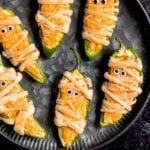Jalapeño popper mummies sit on a black plate