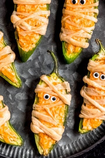 Jalapeño popper mummies sit on a black plate