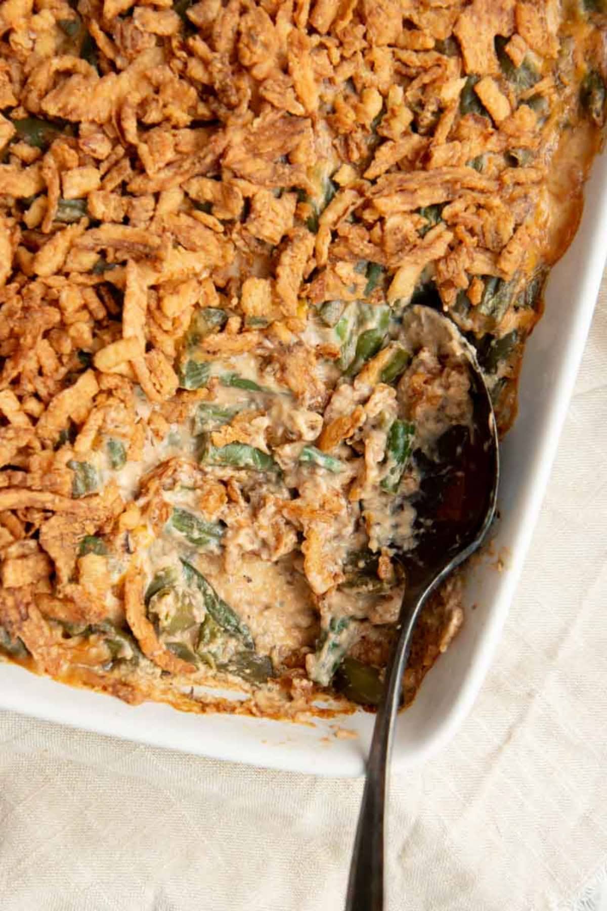 A spoon dips into a dish of fresh green bean casserole.