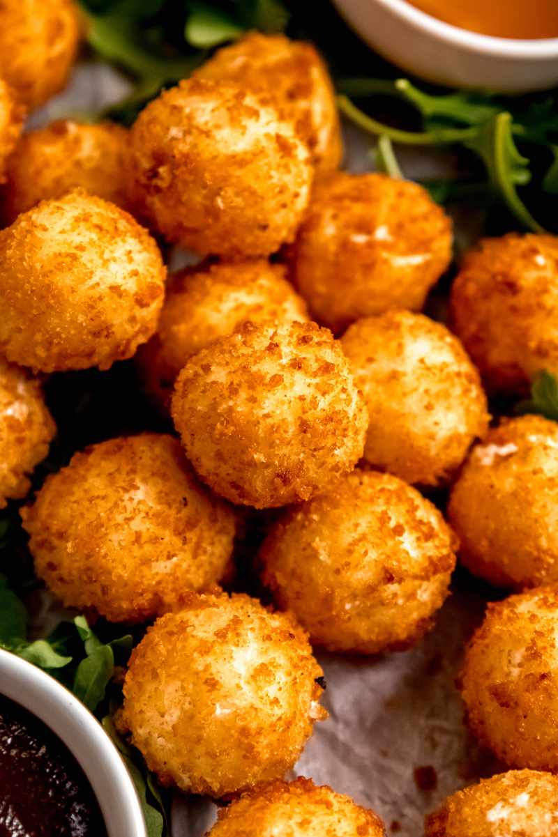 Close view of fried goat cheese balls piled on an appetizer tray.