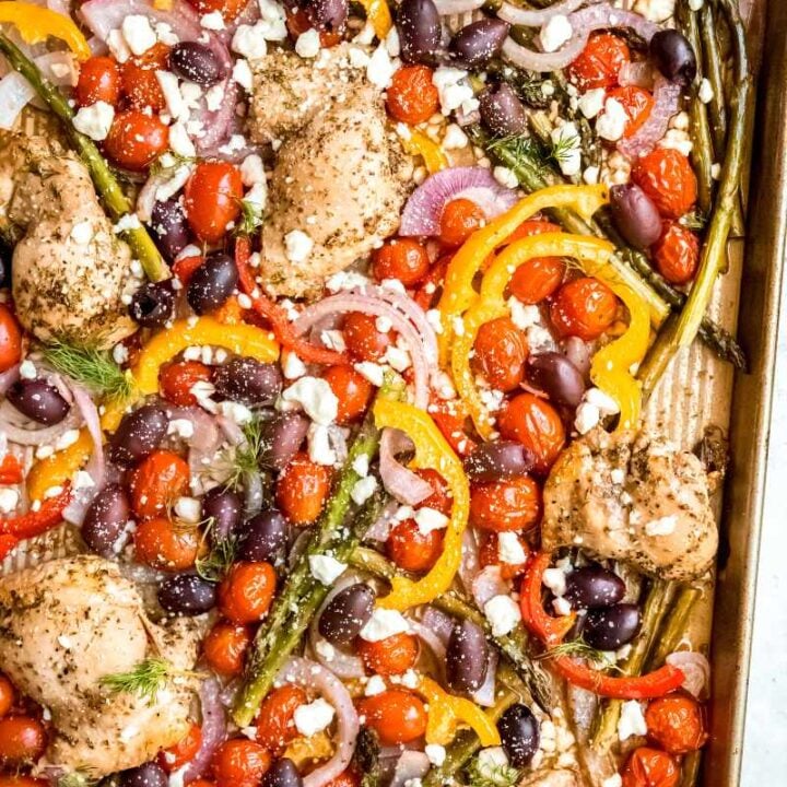Overhead of greek chicken dinner tray bake with veggies and feta cheese.