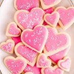 Overhead of a large serving platter of heart-shaped sugar cookies with pink frosting for valentine's day.