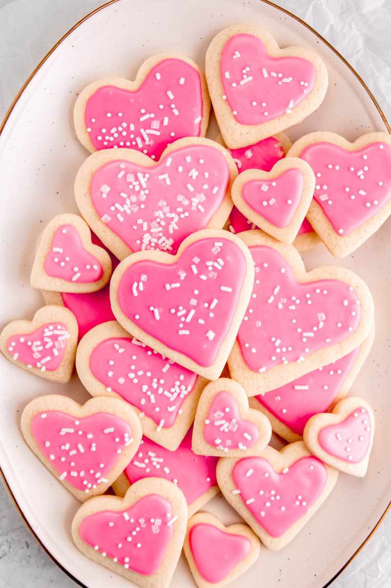 Overhead of a large serving platter of heart-shaped sugar cookies with pink frosting for valentine's day.