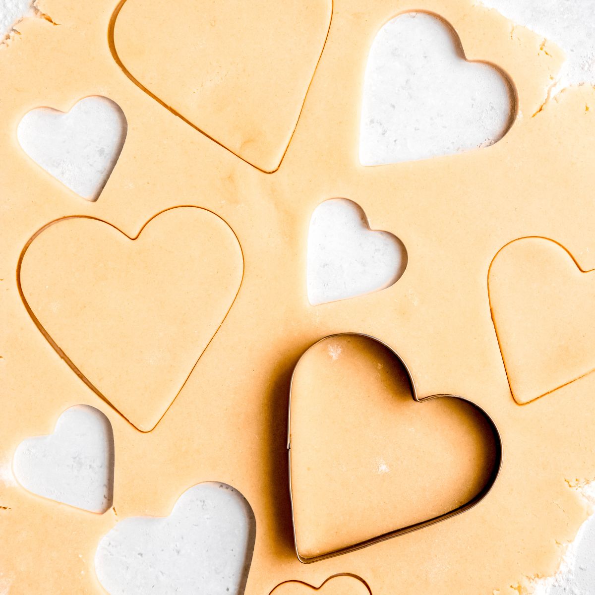 Heart cookie cutter on raw sugar cookie dough