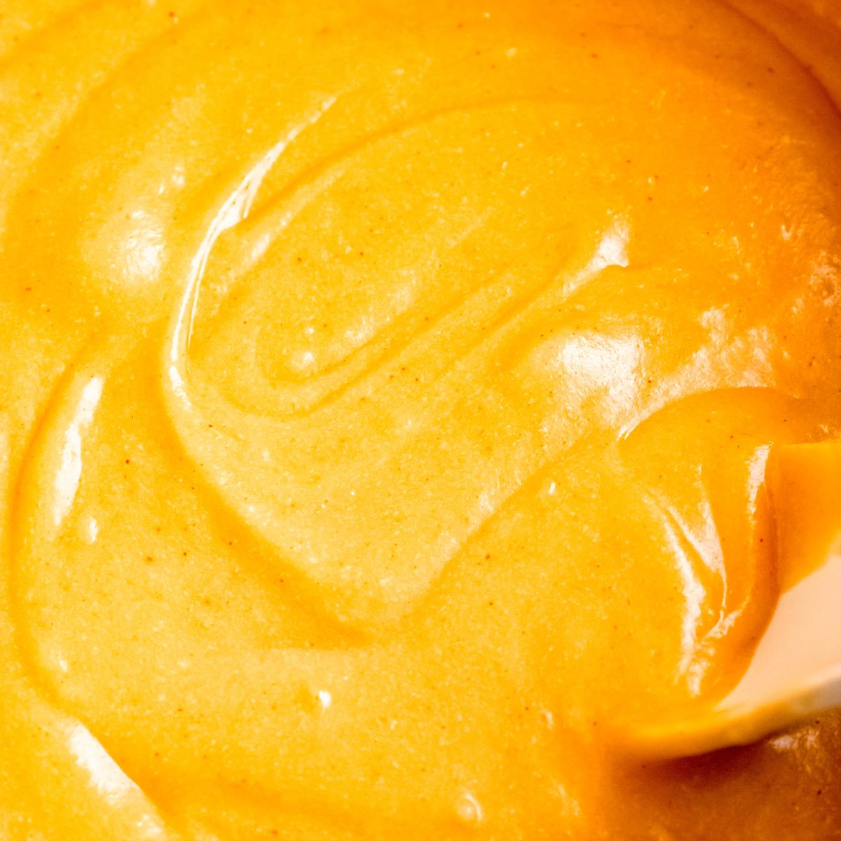 Smooth, creamy beer cheese dip with a spoon pulling through the surface.