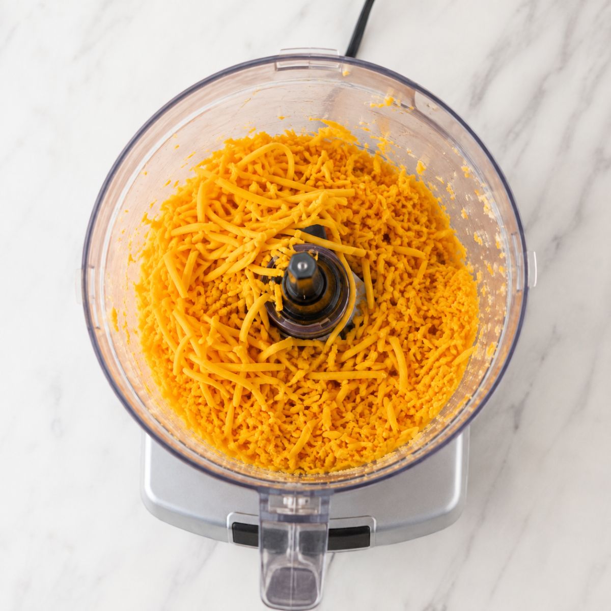 Shredded cheddar cheese inside a food processor