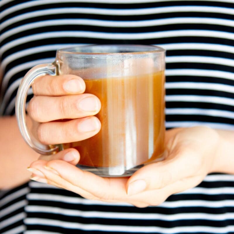 Hands hold a mug of chicken bone broth