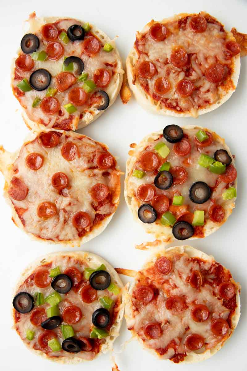 Top view of six English muffin pizzas side-by-side in two columns on a white background.