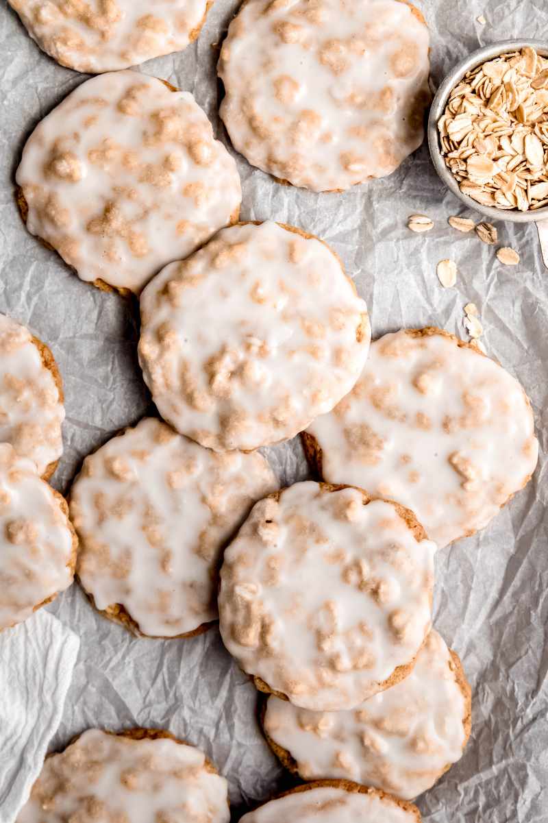 Iced oatmeal cookies served on a parchment paper lined tray.