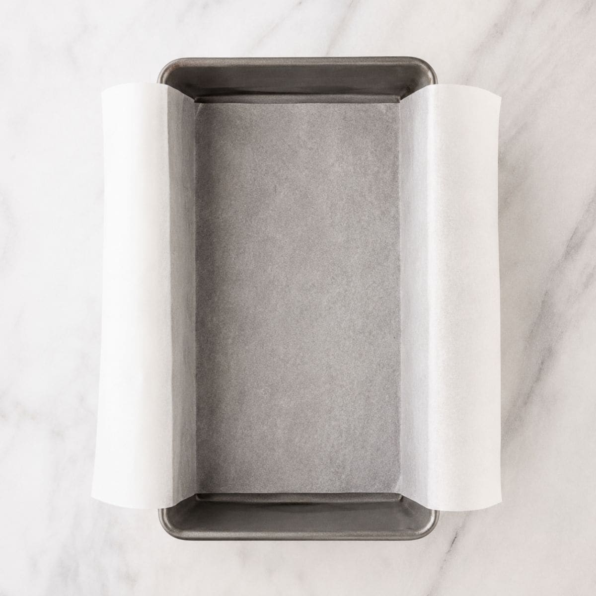 A loaf pan lined with parchment paper, ready for banana bread batter.