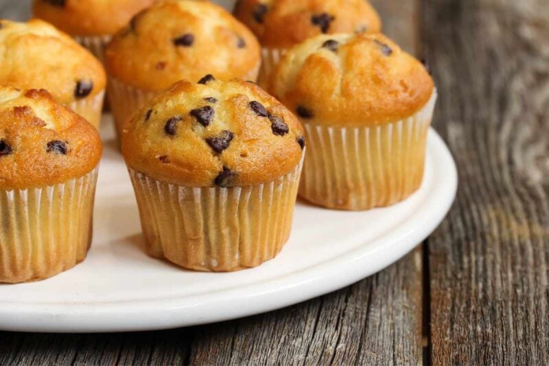 Close view of mini chocolate chip muffins on a white serving dish.