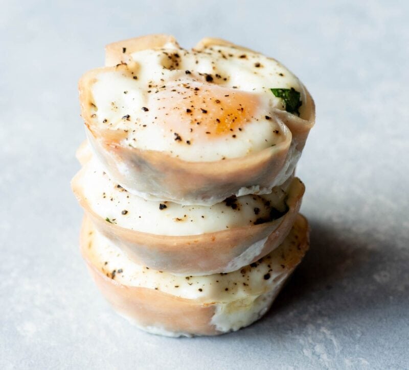 Three spinach egg cups stacked atop one another on a light background.