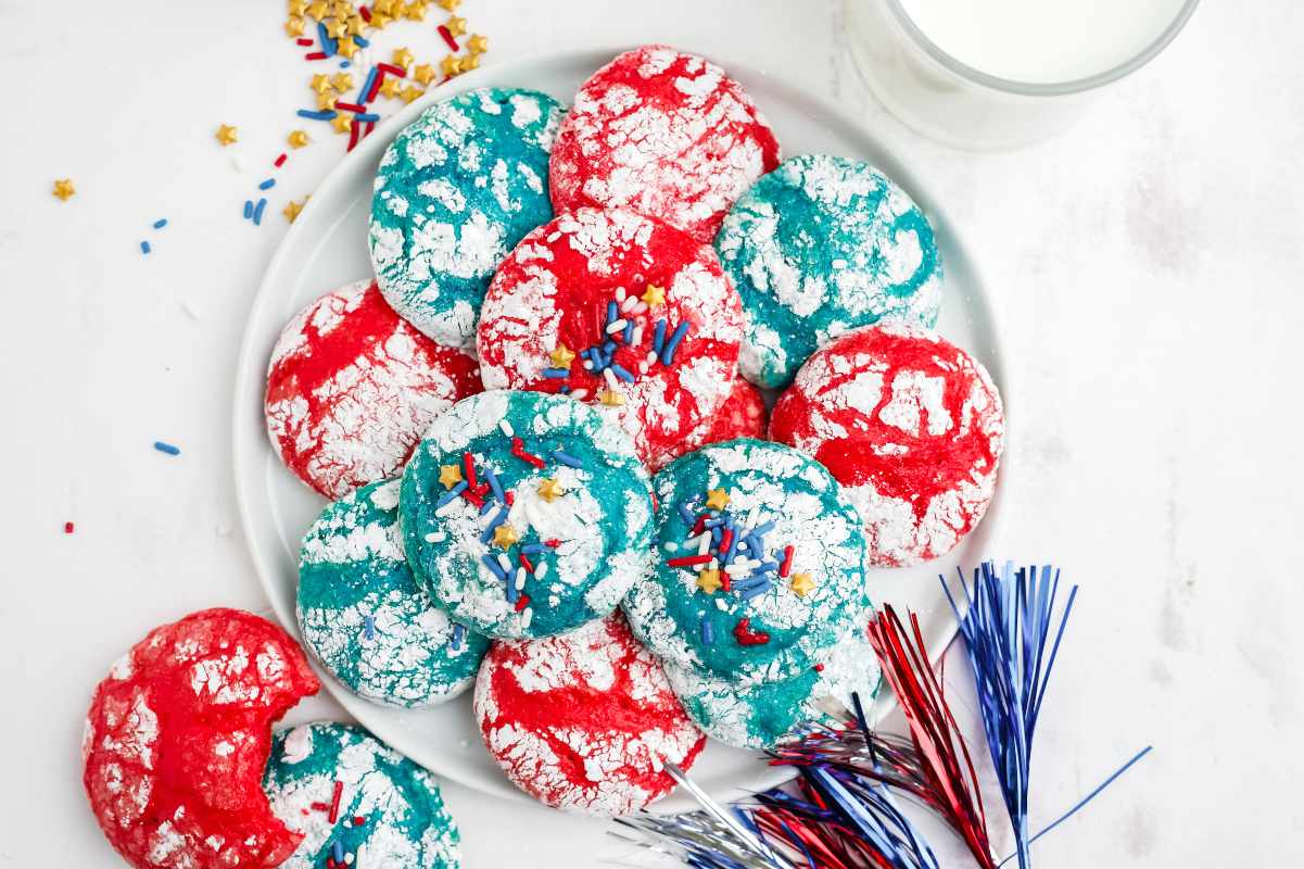 Overhead of red, white, and blue cookies served on a white platter with festive decorations around.