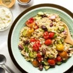 Overhead of a serving of greek barley salad with extra feta and balsamic dressing on the side.