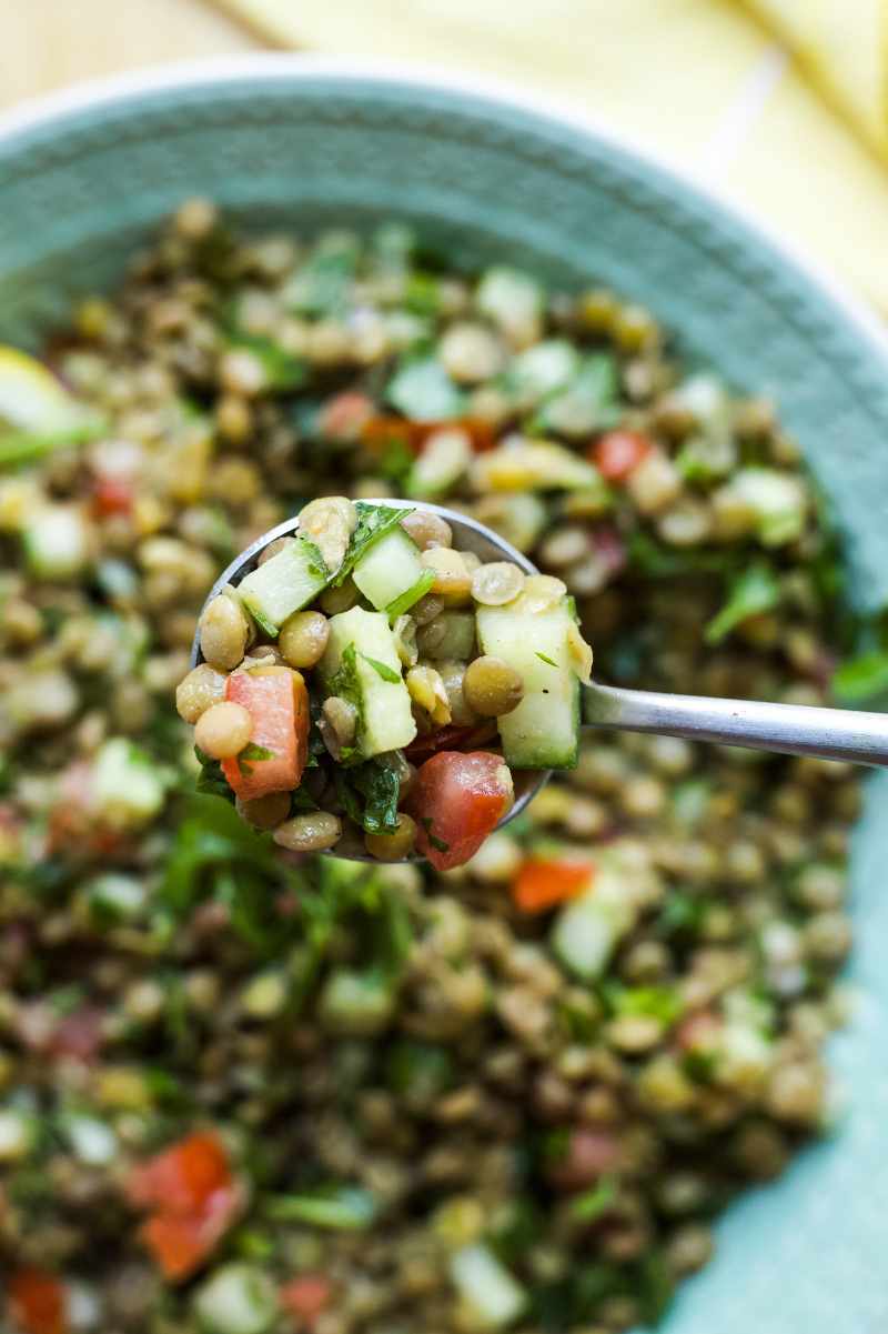 A spoon holds up a bite of lentil tabouli.
