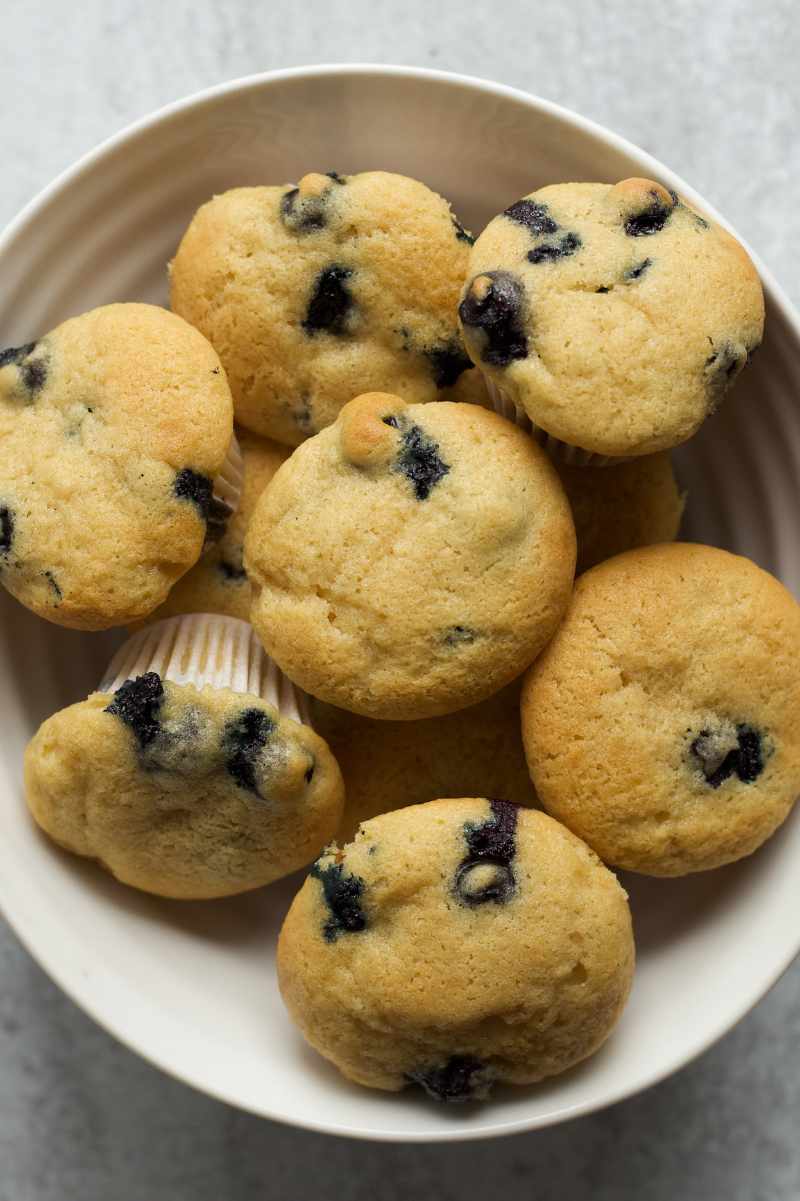 Top view of mini blueberry muffins piled high in a bowl.