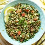 Overhead of a serving bowl of lentil tabbouleh with two lemon wedges garnishing the bowl.