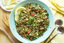Overhead of a serving bowl of lentil tabbouleh with two lemon wedges garnishing the bowl.