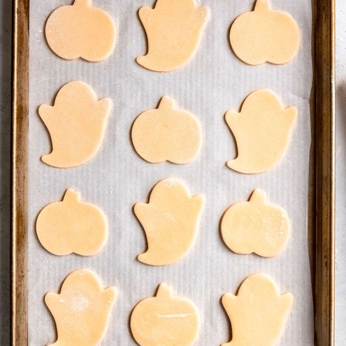 Unbaked Halloween shaped cookies on a baking sheet