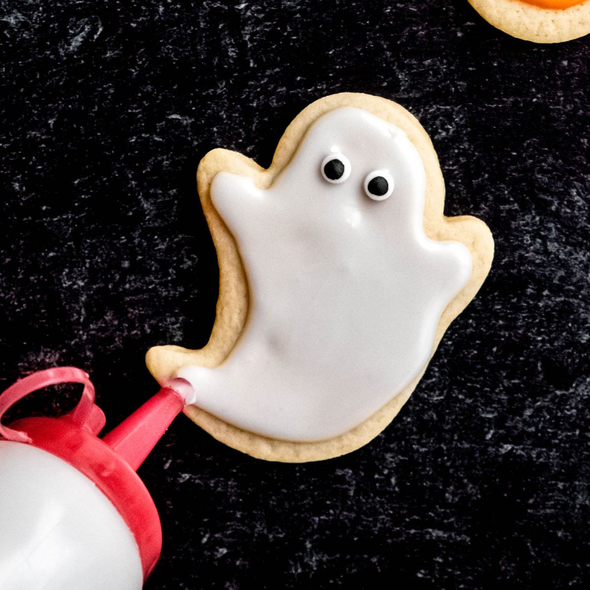 Frosting a ghost sugar cookie with white icing