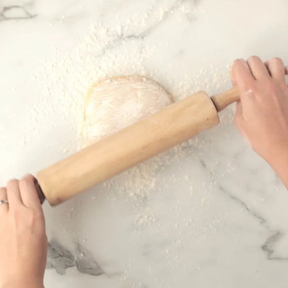 Hands roll out sugar cookie using a rolling pin