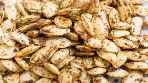 A pile of homemade roasted pumpkin seeds on a piece of parchment paper