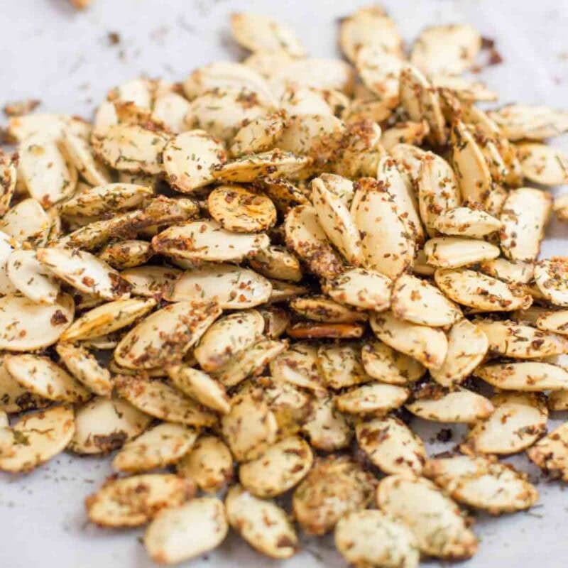 A pile of homemade roasted pumpkin seeds on a piece of parchment paper