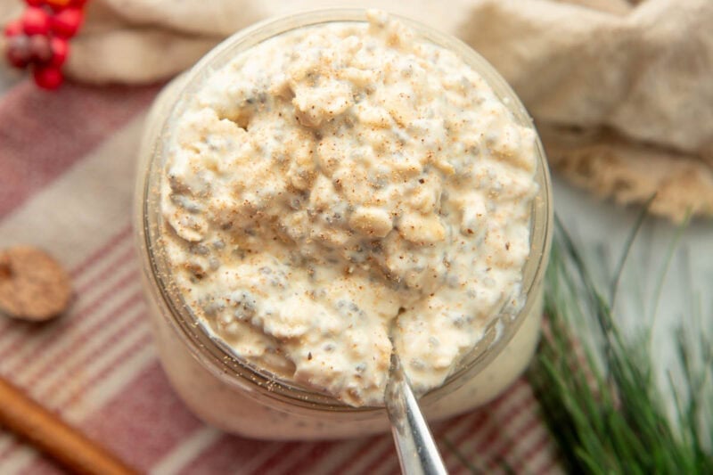 Close view of fresh ground nutmeg dusted across the top of a jar of overnight oats.