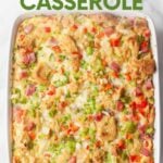 Close view of a breakfast bake studded with red and green peppers, ham, and bread cubes. A text overlay reads, "Denver Omelet Casserole."