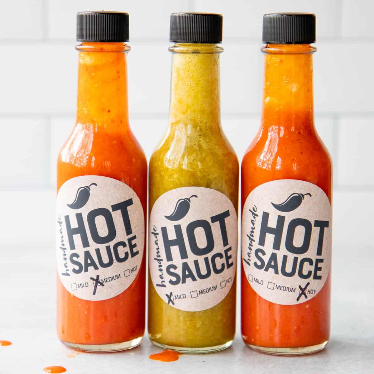 Three bottles of from my hot sauce recipe, lined up on a counter.